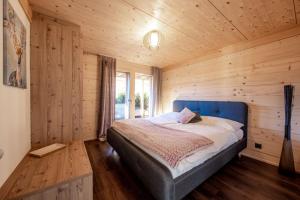 ein Schlafzimmer mit einem blauen Bett an einer Holzwand in der Unterkunft Chalet CARVE - Apartments EIGER, MOENCH and JUNGFRAU in Grindelwald