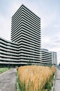 a tall building with a field of grass in front of it at Svarog Unique Apartment in Bratislava
