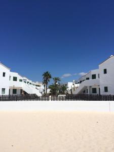 a row of white buildings on a sandy beach at El bañadero in El Cotillo