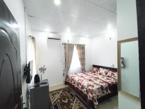 a small bedroom with a bed and a mirror at Cosmetro Homes Abuja in Abuja