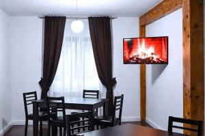 a dining room with a table and a tv on the wall at Pensiunea Cheile Repezii in Borşa
