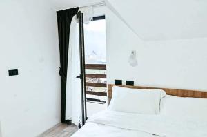 a bedroom with a white bed and a window at Pensiunea Cheile Repezii in Borşa