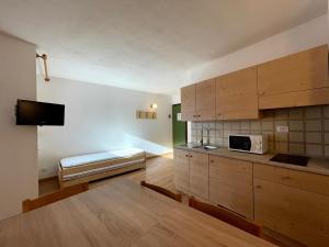 - une cuisine avec des placards en bois et un lit dans une chambre dans l'établissement Casa Mammolo Falcade, à Falcade