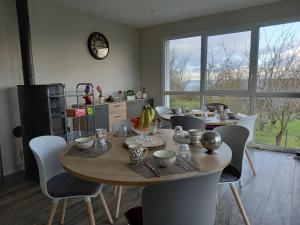 a dining room table with chairs and a clock on the wall at Les Lys in Cricquebœuf