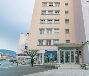 a tall building with a person standing in front of it at apparthotel-gare-chambery in Chambéry