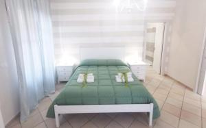 a bedroom with a green bed in a white room at B&B I Pini in Recale
