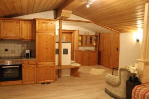 kuchnia z drewnianymi szafkami, stołem i lodówką w obiekcie Appartementhaus FICHTERN w mieście Sankt Johann in Tirol