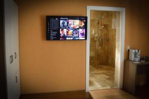 a bathroom with a shower and a television on the wall at Pensiunea La Rogo in Vulcan