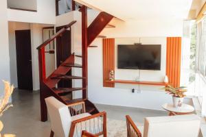 a living room with a spiral staircase and a tv at Morro Apartment Vista Mar in Morro de São Paulo