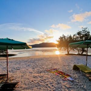 a beach with umbrellas and a towel on the sand at OPY CAMBOA in Governador Celso Ramos