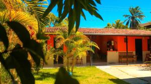 una casa roja con palmeras delante en Pousada Beija-flor en Salinas da Margarida