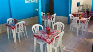 a group of white tables and chairs with flowers on them at Pousada Beija-flor in Salinas da Margarida
