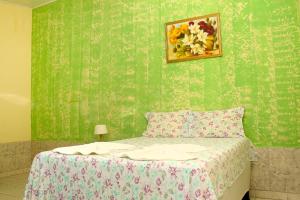 a bedroom with a bed with a green wall at Pousada Beija-flor in Salinas da Margarida