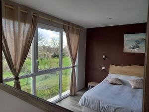 1 dormitorio con cama y ventana grande en Les Lys, en Cricquebœuf