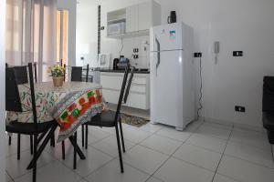 a kitchen with a table and a white refrigerator at Apto Ubatuba Condomínio Sun Way Piscina Churrasqueira in Ubatuba