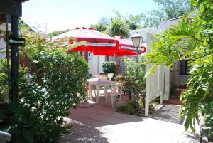 a patio with a table and a red umbrella at Knysna Inn in Knysna