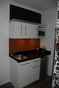 a small kitchen with a sink and a microwave at Knysna Inn in Knysna