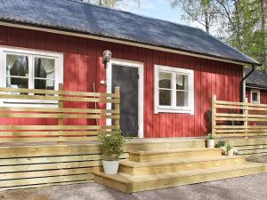 ein rotes Haus mit einer Holzveranda und einem Haus in der Unterkunft 7 person holiday home in SKYLLBERG in Skyllberg