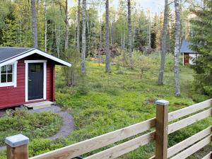 eine rote Hütte im Wald mit einem Zaun in der Unterkunft 7 person holiday home in SKYLLBERG in Skyllberg
