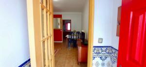 a hallway with a red door leading to a kitchen at Casa dos Buizinhos in Porto Covo