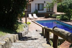 una piscina en un patio con 2 sillas y una casa en Hotel Selva Montana en San Lorenzo