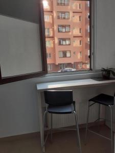 uma secretária com 2 cadeiras num quarto com uma janela em Luxury 1 Bedroom Apartment em Roşu