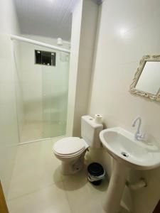 a bathroom with a toilet and a shower and a sink at Residencial Wall Paraíso in Itapema