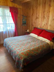 ein Schlafzimmer mit einem Bett in einem Zimmer mit Holzwänden in der Unterkunft Cabaña en Coñaripe Sector Termas Geométricas in Coñaripe