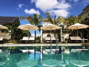 a swimming pool with umbrellas and tables and chairs at Karst Villas Phong Nha in Phong Nha