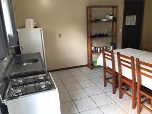 a kitchen with a stove and a table with chairs at Departamentos Vale Encantado in Bombinhas +10 photos