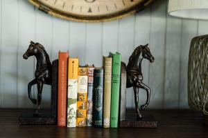 un estante con libros y dos estatuas de caballos. en Walnut Tree Cottages en Whorouly