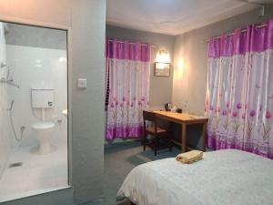 a bedroom with a bed and a desk and a bathroom at Orchid Home Bed & Breakfast pvt ltd in Kathmandu