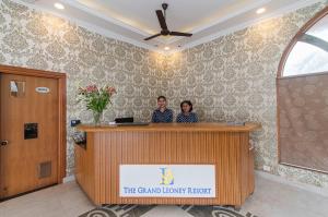 a man and a woman standing at a reception desk at The Grand Leoney Resort in Vagator