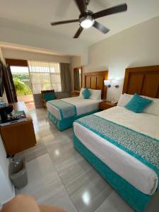 Habitación de hotel con 2 camas y ventilador de techo. en Hotel Posada Quinta Las Flores en Cuernavaca