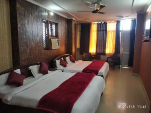 a hotel room with two beds with red blankets at Hotel Aarti Darshan in Haridwār