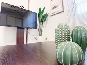 - une table avec une télévision et deux cactus verts dans l'établissement OUCHI HOTEL Dambara, à Hiroshima