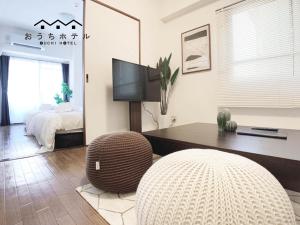 a living room with a bed and a table and a chair at OUCHI HOTEL Dambara in Hiroshima