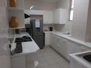 La cuisine est équipée de placards blancs et d'un réfrigérateur en acier inoxydable. dans l'établissement 202 Ipanema Beach, à Durban
