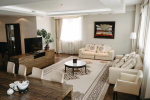 sala de estar con muebles blancos y TV en Hotel Mergen Bator, en Ulan-Ude