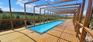 a swimming pool on a wooden deck with a pergola at Endless Vineyards at Wildekrans Wine Estate in Botrivier