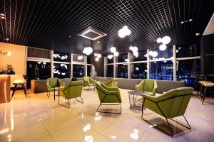 poczekalnia z zielonymi krzesłami, stołami i oknami w obiekcie Ocean The Point Hotel w Pusanie