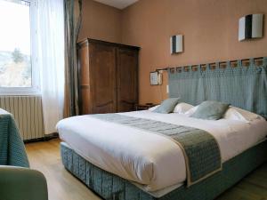 a large bed in a room with a large window at Hôtel Restaurant Le Grillon in Chambon-sur-Lac