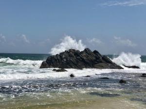 a wave crashing on a rock in the ocean at Rockside Cabanas Hotel in Unawatuna