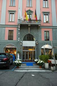 un edificio rosa con banderas encima en Arli Hotel Business and Wellness, en Bérgamo