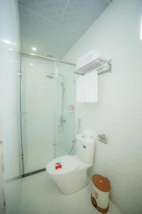 uma casa de banho branca com um chuveiro e um WC. em Nhật Nguyên Hotel em Da Lat
