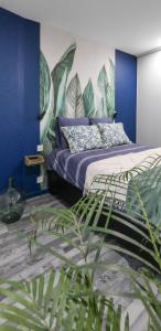 ein Schlafzimmer mit einem Bett mit blauen Wänden und einer Pflanze in der Unterkunft Appartement classé 3 étoiles - Canohès in Canohès