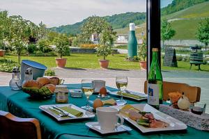 a table with a green table cloth with food and wine glasses at Gästehaus und Weingut Bernd Frieden in Nittel