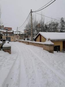 una calle cubierta de nieve con techos y edificios cubiertos de nieve en Apartamentos Rurales Camino del Cid, en Castejón de las Armas
