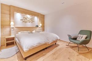 a bedroom with a large bed and a green chair at Boutique Hotel Beau-Séjour & Spa Superior in Champéry