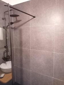 a shower in a bathroom with a gray tile wall at Apartament KUBIKS SADY in Malbork